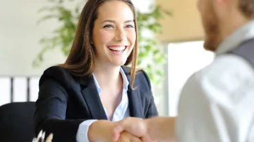 seated woman in corporate wear shaking hands with someone
